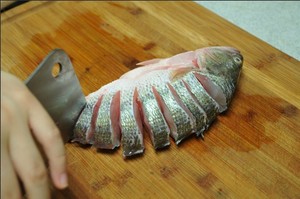 將鱸魚清洗干凈，從脊椎處切斷至腹部，腹部保留1cm左右不要切斷。