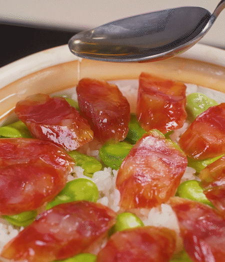 大米出現(xiàn)小孔時(shí)開(kāi)蓋放香腸，往鍋邊淋入少許油，再燜煮8~10分鐘左右。